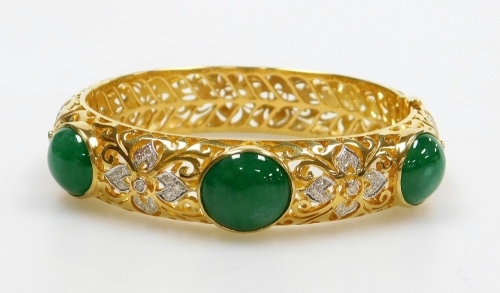 An ornate jade and diamond set hinged bangle, three cabachon jade stones of 11.3mm x 9.1mm approx each, on an ornate carved hollow bangle with tiny diamond set accents to the front, internal diameter 5.2cm, external diameter 6.5cm, 1.2cm wide, 51.4g all i