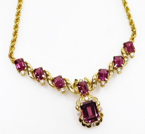 A tourmaline and diamond set necklace, seven stones of 6.5mm x 4.9mm rectangular facet cut and one of 11.mm x 8.2mm, with tiny diamond accents, on S scroll links to figaro chain supports, 45cm long approx, 21.8g all in.