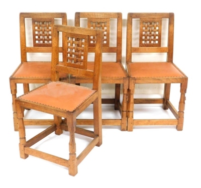 A set of four Robert Thompson Mouseman oak dining chairs, with a lattice back and leather studded seat, on block supports united by stretchers, model number CH050, 85cm high. NB. We have specific vendor instructions to SELL WITHOUT RESERVE.