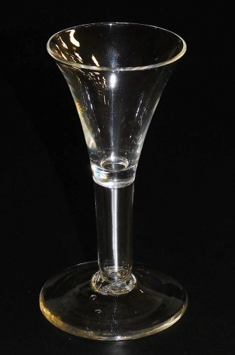 A late 18thC wine glass, possibly an Excise glass, with a trumpet shaped bowl and plain stem, raised on a conical foot, 12.5cm high.