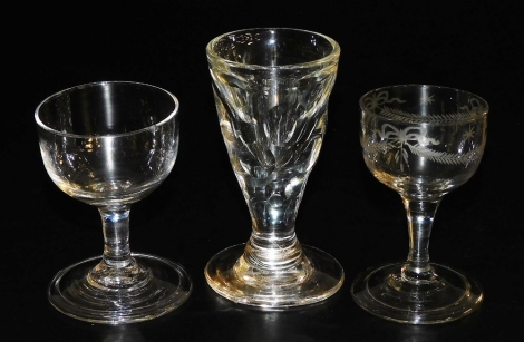 A late 18thC Georgian dram glass, raised on a straight stem and conical folded foot, further glass with a wreath, bow and star engraved bowl, and a deceptive glass. (3)