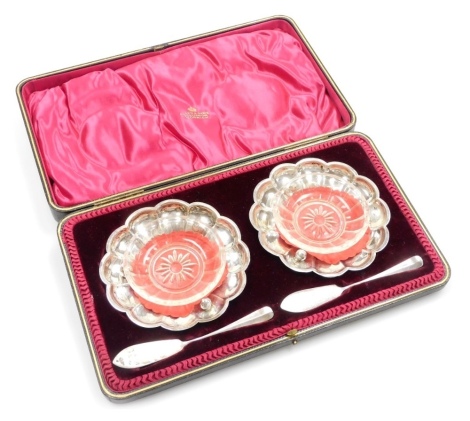 A pair of Edwardian silver butter dishes and spoons, each with a glass liner, retailed by Allen & Dows Norwich, in a fitted case, Sheffield 1902, 5.3g.