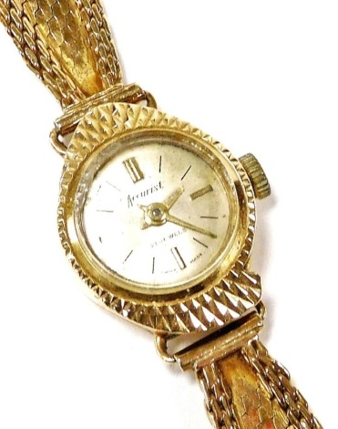 An Accurist lady's 9ct gold cased wristwatch, circular champagne dial with gilt batons, twenty one jewel movement, on an integral mesh gold strap, 14.8g.