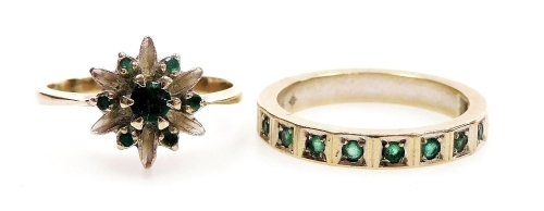 An emerald flower head ring, set in white metal, stamped 585, size L, and an emerald half hoop eternity ring, set in white metal, stamped 585, size M, 6.0g.