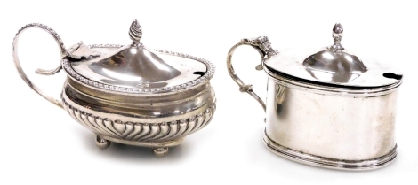 A George V silver mustard pot, of plain oval form with acorn finial and raised line decoration to rim and base, with blue glass liner Chester 1913, 2.15oz, 6cm high, and a Victorian silver mustard pot with raised beaded rim and handle, the part fluted bod