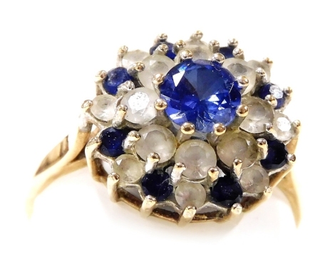 A 9ct gold and gem set concentric flower head ring, set with blue and white stones, possibly sapphires, size T, 3.5g.