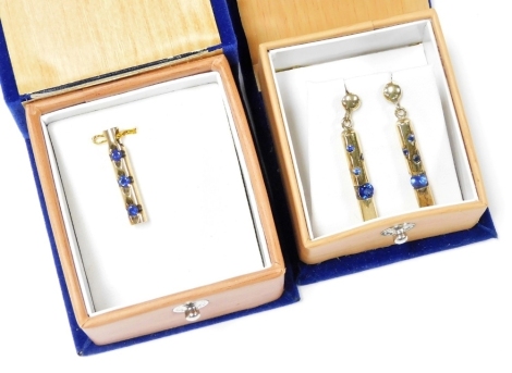 A Ceylon sapphire three stone pendant, set in yellow metal, of cylindrical form, together with a pair of similarly designed pendant earrings, of cylindrical form each set with one large and three small sapphires, in yellow metal, 9.6g.