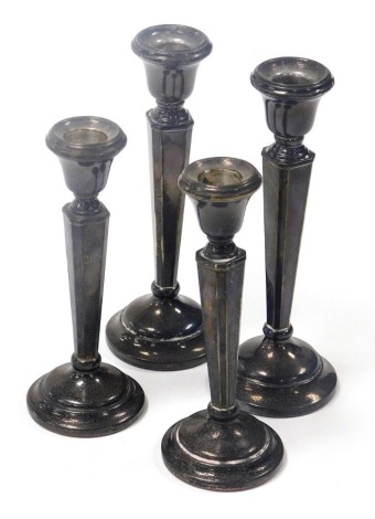 Two pairs of Elizabeth II silver candlesticks, each with an angular body and stepped base, loaded, Birmingham 1976 and 1977, 18.5cm and 16cm high.