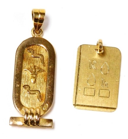 An oval pendant, decorated with hieroglyphs against a textured ground, yellow metal, 6.5g, and a further engraved pendant, yellow metal, 2.8g. (2)