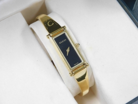 A Gucci lady's gold plated wristwatch, rectangular black dial, back engraved number 06803, on a bracelet strap, boxed with warranty.