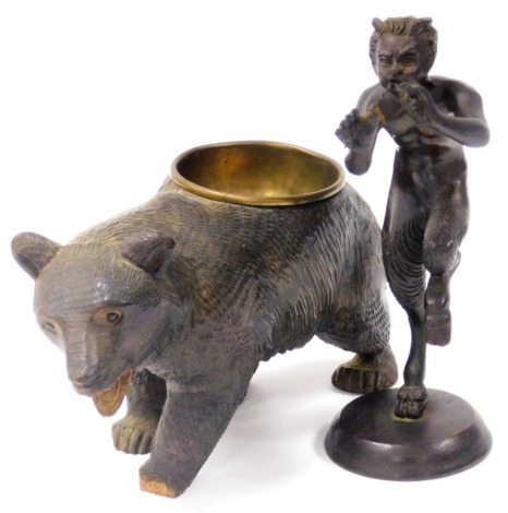 An early 20thC bronze figure of Pan, modelled standing playing his pipes, on a circular base, unsigned, 18cm high, and a Black Forest bear ashtray inset with a brass bowl, 19.5cm wide. (2, AF)