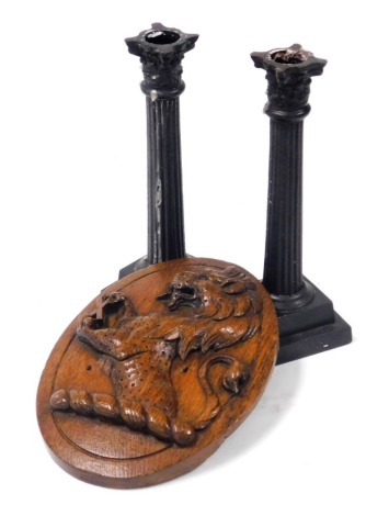 A Victorian oval oak plaque, carved with a heraldic crest of a rampant lion, 18.5cm high, together with a pair of bronze Corinthian column candlesticks, 19cm high. (3)