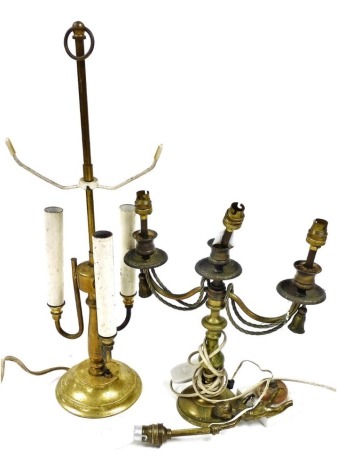 Three table lamps, comprising a brass figure of a putto holding a lamp, on a marble base, 33cm high, a brass candelabrum, the shaped arms with draped brass rope and tassel decoration, 38cm high, and an early 20thC brass table lamp, with three shaped light