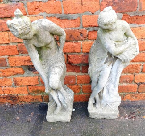 A pair of reconstituted stone garden statues, of a female water carrier, and a further female washing, 78cm high.