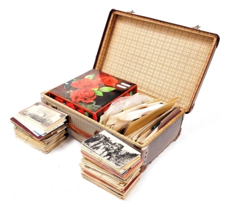 Deltiology and philately, including early 20thC European postcards, and 19thC and later postage stamps, British and world, in a small stamp album and a suitcase of envelopes.