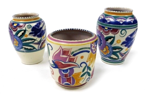 Three mid century Poole pottery vases, two painted with swallows and flowers, 16cm and 15cm high, the third with stylised flowers, 12.5cm high.