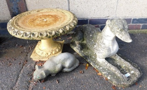 A concrete garden ornament modelled as a recumbent greyhound, 69cm wide, reconstituted stone bird bath, 51cm diameter, and a concrete figure of a cat, 34cm wide. (3)