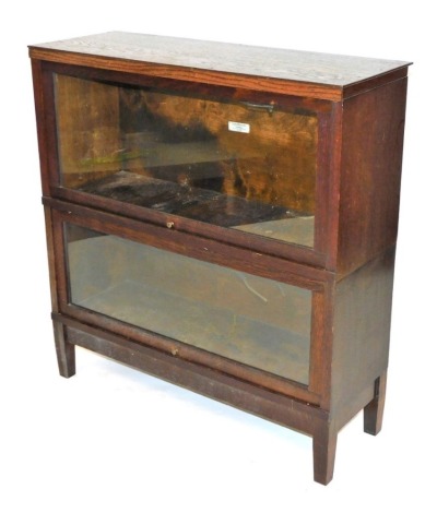 A Globe-Wernicke Universal Elastic bookcase, marked to side 813, of two section form, with glass fronted up and over doors, raised on square legs, 92cm high, 87.5cm wide, 32cm deep.