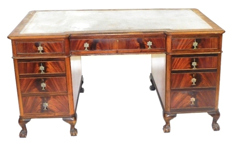 An early 20thC flame mahogany inverted breakfront pedestal desk, with a tooled grey leather top, over one long flanked by eight short drawers, raised on cabriole legs and ball and claw feet, 78cm high, 152cm wide, 90cm deep.