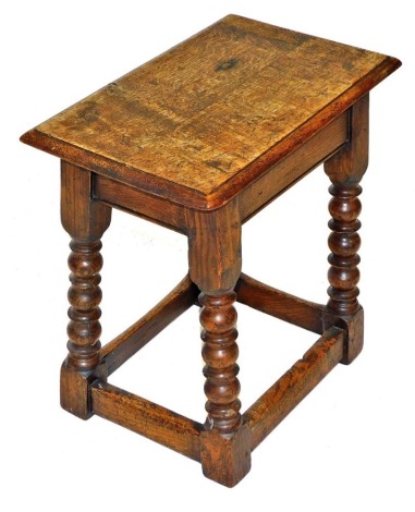 An oak joint stool, raised on bobbin turned supports united by a box stretcher, 45cm wide.