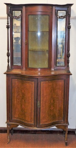 A Victorian mahogany, satinwood cross banded and marquetry inlaid display cabinet, the top with a convex glass fronted cabinet, three shelves flanked by two mirrored panels, above two doors enclosing a single shelf, raised on tapering, square legs, on spa