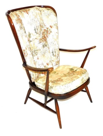 An Ercol dark elm and beech comb back armchair, with open arms and floral patterned loose cushions. 73cm wide. The upholstery in this lot does not comply with the 1988 (Fire & Fire Furnishing) Regulations, unless sold to a known exporter or upholsterer it