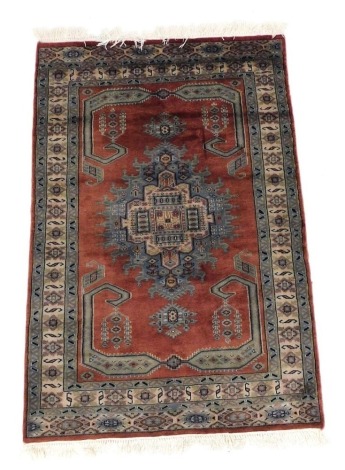 A Turkish Oushak terracotta ground rug, with central lozenge within floral and geometric borders, 170cm x 111cm.