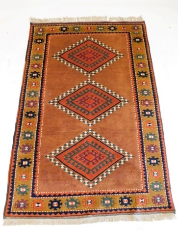 A Turkish Kilim brown ground rug, decorated with three central diamond shaped medallions, within repeating geometric borders, 194cm x 131cm.