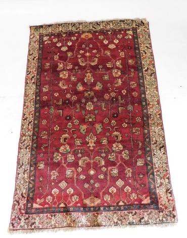 A Persian Kamseh rug, decorated with floral motifs against a red ground, within repeating floral borders, 180cm x 120cm.