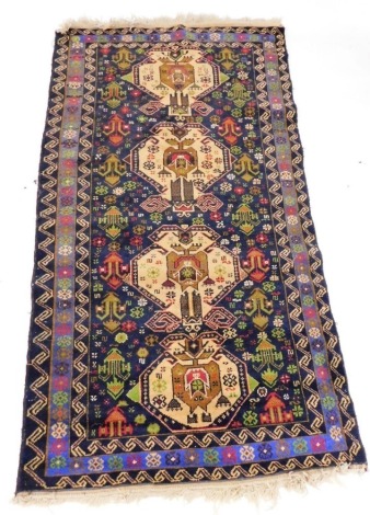 A Caucasian blue ground rug, decorated with four central floral medallions, against a floral pattern ground, within repeating borders, 190cm x 107cm.