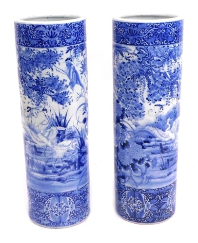 A pair of Japanese blue and white stick stands, each with a bird of prey and floral spray design, unmarked, each 77cm high, 26cm diameter.