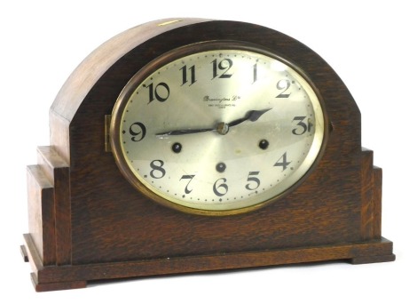 A Bravingtons Limited of Kings Cross and Ludgate HIll London oak cased mantel clock, in the Art Deco style with stepped sides and silvered oval numeric dial, with eight day movement and chime, 23cm high, 35cm wide, 16cm deep.