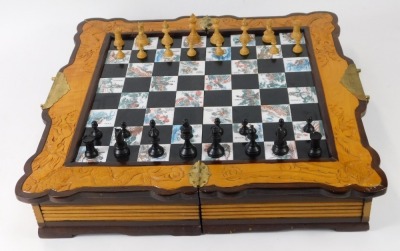 Two chess sets, comprising a Chinese camphorwood folding chess set, with engraved panels of figures and animals, and a further travel example with draughts and dominoes, the largest board 48cm x 50cm. (AF) - 2