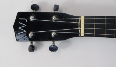 A W J Music ukulele, bearing label Model WJ-UK-BK, in black, with material carry case, 54cm high. - 3