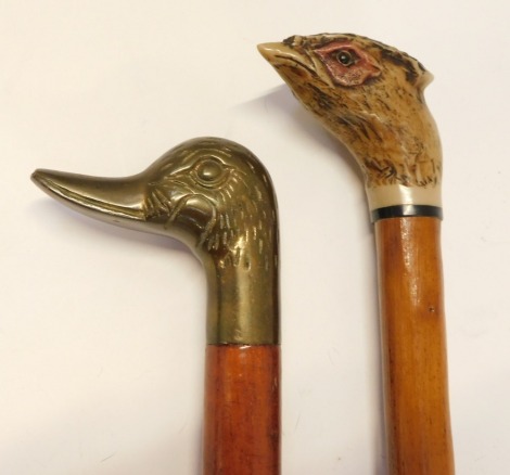 Two walking sticks, comprising a brass duck handled stick and a resin pheasant mounted stick, 93cm long.