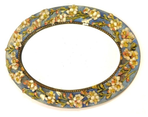 A Barbola style oval wall mirror, with a blue and cream painted panel and applied flowers and berries, with oval mirror plate, 44cm x 30cm.