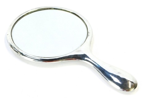 A hand held dressing table mirror, with circular top, in a white metal case, hallmark rubbed.