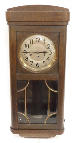 A 1930's/1940's Junghans oak cased wall clock, the moulded cornice above a silvered numeric dial, with a thirty hour chiming movement, 83cm high, 35cm wide, 20cm deep.