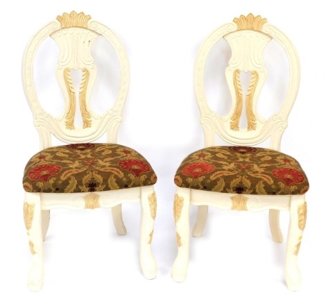 A pair of cream painted balloon back hall chairs, the pierced splat with a moulded crest, on floral upholstered seats and cabriole legs, 110cm high. The upholstery in this lot does not comply with the 1988 (Fire & Fire Furnishing) Regulations, unless sol