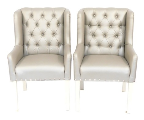 Two leather effect silver wingback armchairs, each with cream painted legs, purchased originally from Andrew Martin of Walton Street, 107cm high, 64cm wide, 64cm deep.