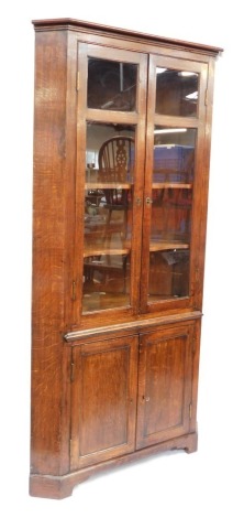 A 19thC oak standing corner cabinet, with a display cabinet top, with three shelves and two cupboard doors to the base on bracket feet, 199cm high, 104cm wide, 69cm deep.