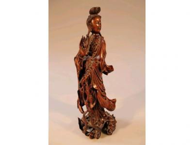 A 19thC Chinese carved mahogany figure of Guanyin supported on a carved