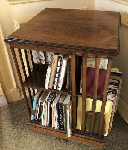 A late Victorian rosewood revolving bookcase, on X framed base, 82cm high, 50cm wide, 50cm deep.