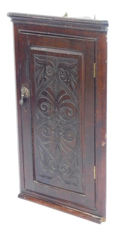 A late 19thC oak hanging corner cabinet, with single panelled door with glazed scroll and flower detail, moulded cornice, 80cm high, 46cm wide and 30cm deep.