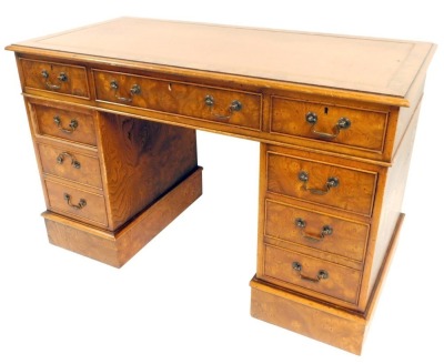 A burr elm pedestal desk, the top with a brown leather inset top, above nine drawers, on a plinth, 80cm high, 123cm wide, 62cm deep.