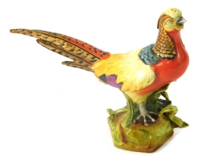 A Continental porcelain figure of a pheasant, on a rocky ground, with yellow, purple and orange colouring, 20cm high.