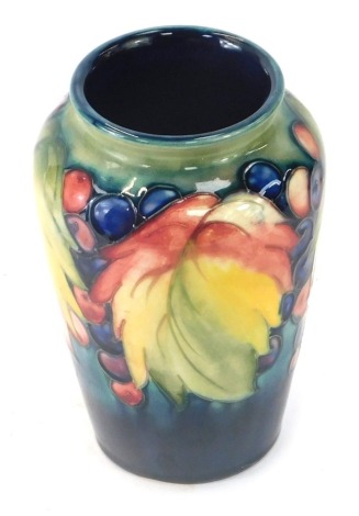 A William Moorcroft vase decorated in the leaf and berry pattern, signed W Moorcroft, stamped Made in England, 15cm high.