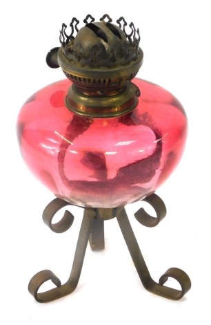 A 19thC cranberry glass oil lamp, on a brass shaped tripod base, 27cm high.