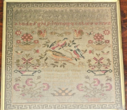 An early Victorian alphabetic pictorial and motto sampler, by Betsy Balls aged eleven years dated 1838, decorated with vases of flowers and birds, with a Greek key border with a flamed mahogany and inlaid frame, the frame 45cm x 44cm.