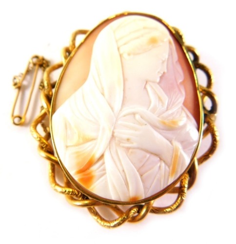 A late 19thC shell cameo brooch, depicting maiden with head scarf, with a yellow metal frame, unmarked, with single pin back and safety chain, with entwined border, 5cm x 4cm, 23.4g all in.